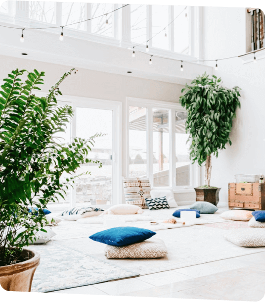 A cozy room filled with colorful pillows and lush green plants, designed for relaxation at Outland Short-Term Rental.